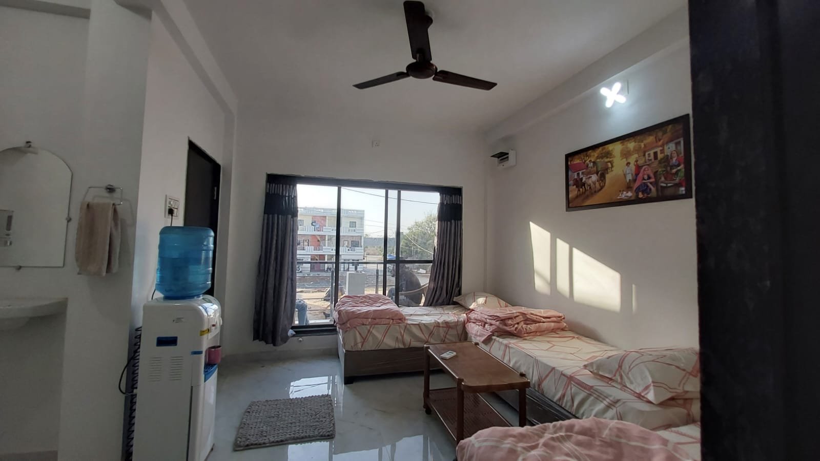 Guest room with twin beds and large window at Madhav Homestay