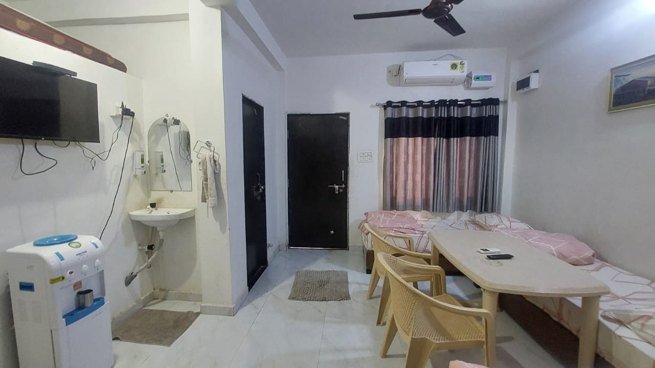 Living area with TV, dining table and seating at Madhav Homestay